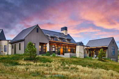 Cette image montre une grande façade de maison marron rustique à un étage avec un revêtement mixte, un toit à deux pans et un toit en métal.