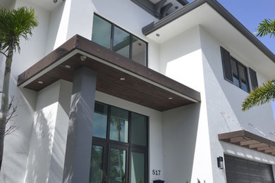 Diseño de fachada de casa blanca actual de tamaño medio de dos plantas con revestimiento de estuco, tejado a cuatro aguas y tejado de teja de barro