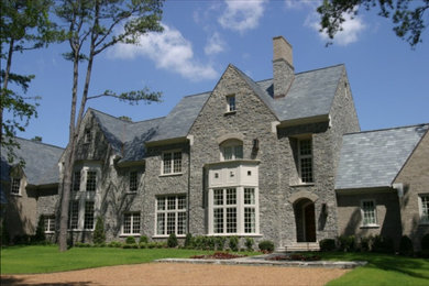Ejemplo de fachada de casa gris clásica grande de tres plantas con revestimiento de piedra, tejado a dos aguas y tejado de teja de madera