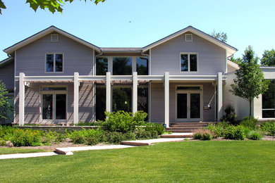 Modelo de fachada gris actual grande de tres plantas con revestimiento de madera y tejado a dos aguas