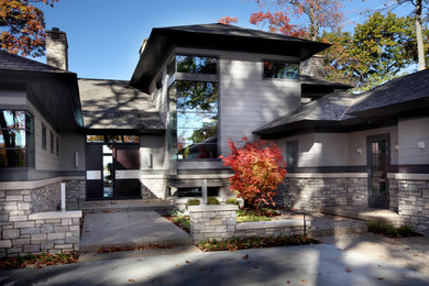 Aménagement d'une façade de maison grise contemporaine en panneau de béton fibré à un étage avec un toit à quatre pans.