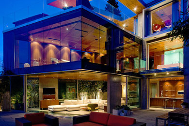 Foto della villa grande contemporanea a tre piani con rivestimento in vetro e tetto piano
