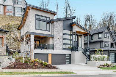 Example of a large trendy gray three-story stucco house exterior design in Vancouver with a shed roof and a shingle roof