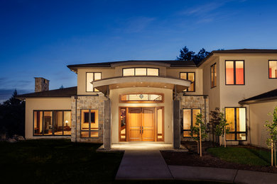 Inspiration for a large contemporary beige two-story stucco exterior home remodel in Portland with a hip roof