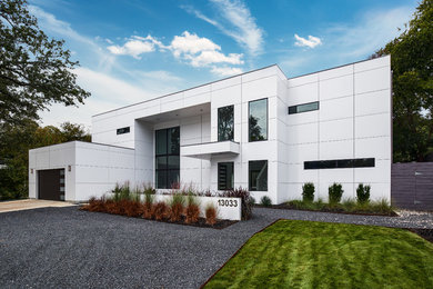 Modelo de fachada de casa blanca minimalista de tamaño medio de dos plantas con revestimiento de aglomerado de cemento, tejado plano y tejado de metal