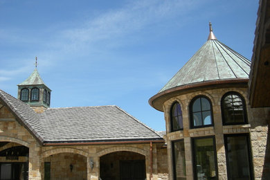 Imagen de fachada de casa beige clásica renovada grande de dos plantas con revestimiento de piedra, tejado a doble faldón y tejado de teja de barro