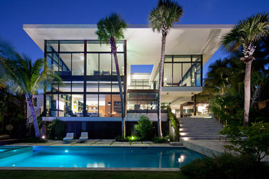 Huge trendy two-story glass flat roof photo in Miami