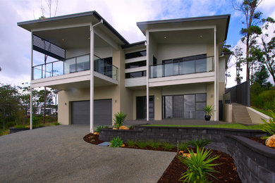 Modelo de fachada beige contemporánea de dos plantas con revestimiento de aglomerado de cemento
