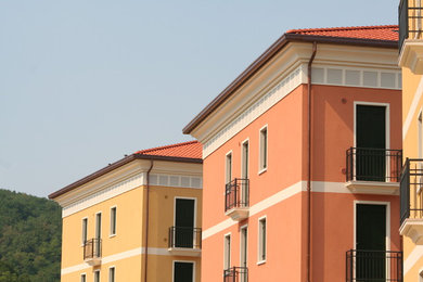Foto della facciata di una casa grande rossa classica a tre piani con rivestimento con lastre in cemento e tetto a padiglione