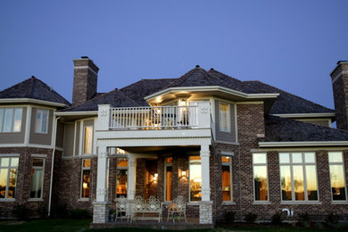 Example of a large transitional brown two-story brick house exterior design in Charlotte with a hip roof and a shingle roof