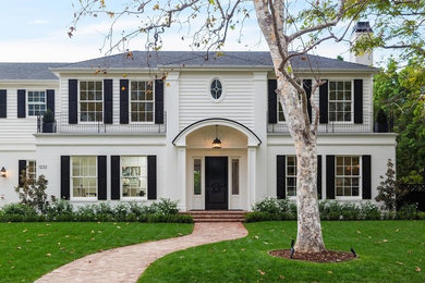 Elegant white two-story house exterior photo in Los Angeles with a hip roof and a shingle roof