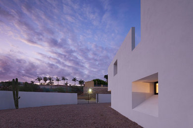 This is an example of a white contemporary two floor concrete detached house in Other with a flat roof.
