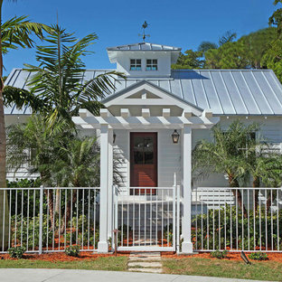 Esempio della facciata di una casa bianca tropicale a un piano di medie dimensioni con rivestimento in legno, tetto a capanna e copertura in metallo o lamiera