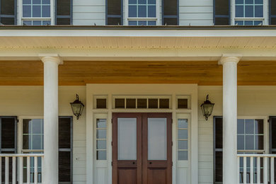 Esempio della facciata di una casa bianca country a tre piani con rivestimento in legno