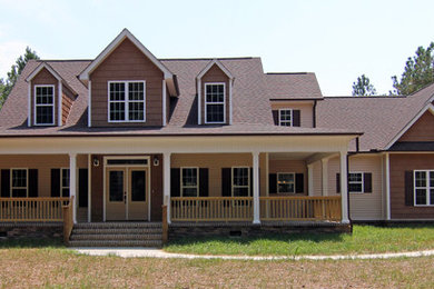 Modelo de fachada marrón de estilo de casa de campo grande de dos plantas con revestimientos combinados