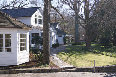 Modelo de fachada blanca de estilo de casa de campo grande de dos plantas con revestimiento de madera y tejado a dos aguas
