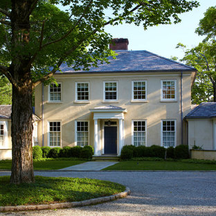 Mid-sized elegant beige two-story stucco house exterior photo in New York with a hip roof and a shingle roof