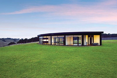 Mittelgroßes, Einstöckiges Modernes Haus mit Glasfassade, schwarzer Fassadenfarbe und Flachdach in Melbourne