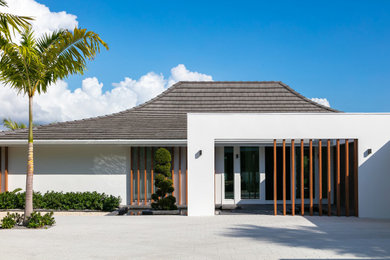 Example of a small 1950s white one-story stucco house exterior design in Tampa with a shingle roof