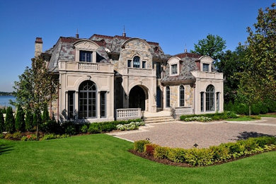Example of a large tuscan beige two-story stone exterior home design in New York
