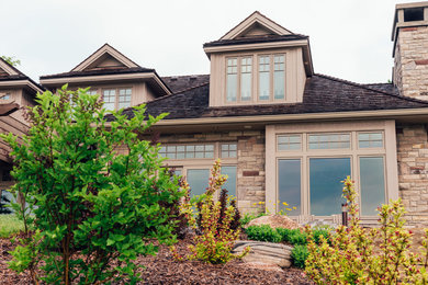 Cette photo montre une façade de maison beige craftsman de taille moyenne et de plain-pied avec un revêtement en vinyle, un toit à quatre pans et un toit en shingle.