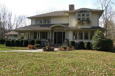 Modelo de fachada de casa beige de estilo americano grande de dos plantas con revestimiento de madera, tejado a cuatro aguas y tejado de teja de madera