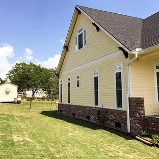 Modelo de fachada de casa amarilla, de estilo americano, de una planta, con revestimiento de madera, tejado a dos aguas y tejado de teja de madera