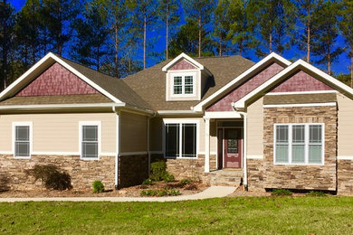 Modelo de fachada de casa beige de estilo americano grande de dos plantas con revestimientos combinados, tejado a dos aguas y tejado de teja de barro
