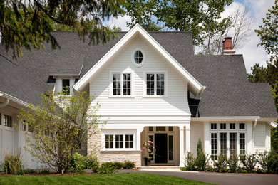 Ejemplo de fachada blanca clásica de dos plantas con revestimiento de madera y tejado a dos aguas