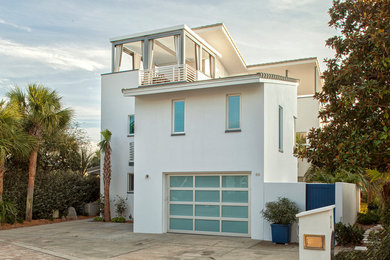 Foto på ett mellanstort funkis vitt hus, med tre eller fler plan, stuckatur, pulpettak och tak med takplattor