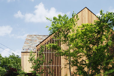 Imagen de fachada marrón de estilo zen de dos plantas con revestimiento de madera y tejado a dos aguas