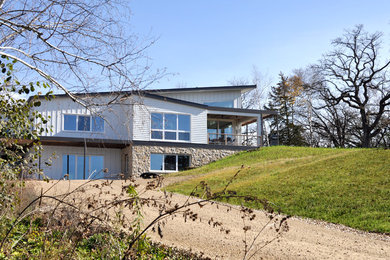 Foto de fachada blanca nórdica grande de dos plantas con revestimiento de aglomerado de cemento y tejado de un solo tendido