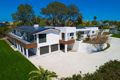 Inspiration for a large contemporary white two-story stucco exterior home remodel in San Diego with a metal roof