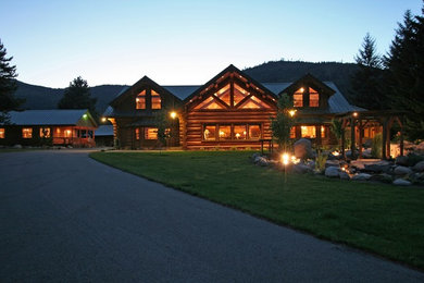 Large mountain style brown two-story wood exterior home photo in Other with a metal roof
