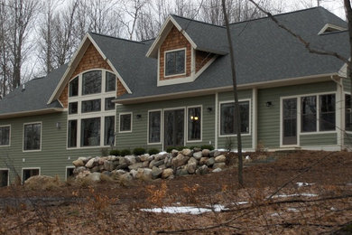 Imagen de fachada de casa verde de estilo americano grande de dos plantas con revestimiento de vinilo, tejado a dos aguas y tejado de teja de madera