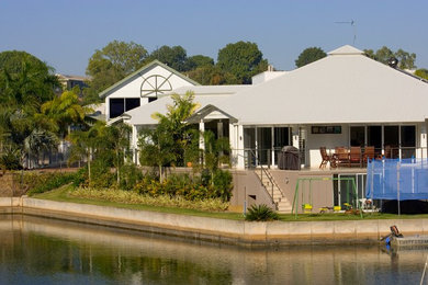 Ejemplo de fachada blanca tropical de tamaño medio de dos plantas con revestimiento de hormigón y tejado a cuatro aguas