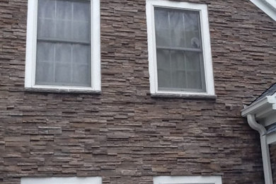 Foto de fachada de casa marrón de dos plantas con revestimiento de piedra