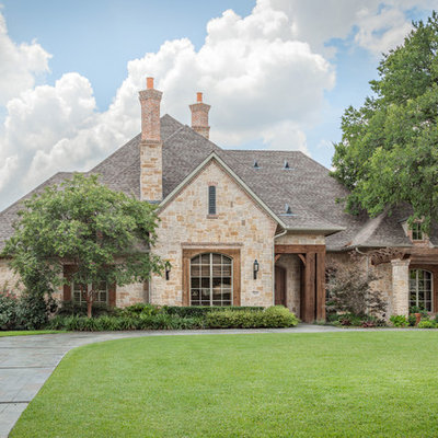 Large traditional beige one-story stone house exterior idea in Dallas with a hip roof and a shingle roof