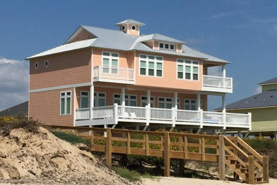 Стильный дизайн: большой, трехэтажный, оранжевый частный загородный дом в морском стиле с облицовкой из винила и металлической крышей - последний тренд