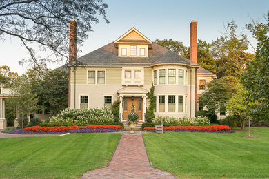 Esempio della facciata di una casa grande verde classica a due piani con rivestimento in legno e tetto a padiglione