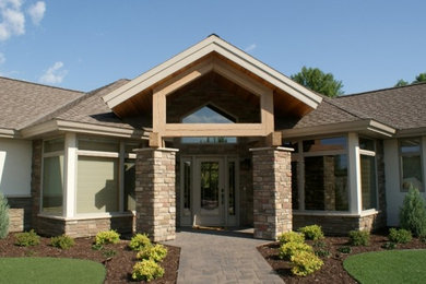 Diseño de fachada de casa beige tradicional de tamaño medio de una planta con revestimiento de estuco, tejado a cuatro aguas y tejado de teja de madera