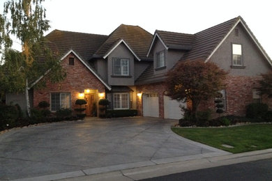 Inspiration for a large timeless two-story brick house exterior remodel in Other with a black roof