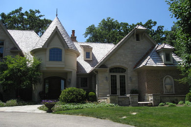 Example of a large classic beige three-story stone exterior home design in Chicago with a gambrel roof