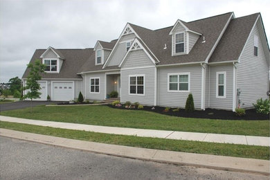 Modelo de fachada de casa gris de estilo americano de tamaño medio a niveles con revestimiento de vinilo, tejado a dos aguas y tejado de teja de madera