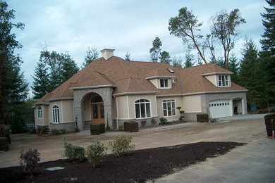 Imagen de fachada de casa beige clásica grande de dos plantas con revestimientos combinados, tejado a cuatro aguas y tejado de teja de madera