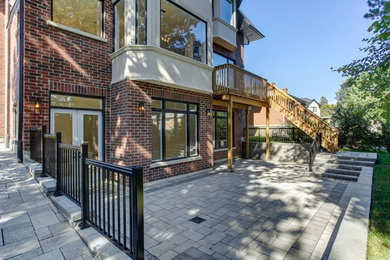 Example of a large red two-story brick house exterior design in Toronto