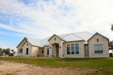 Mid-sized mountain style beige one-story stone exterior home photo in Austin with a metal roof