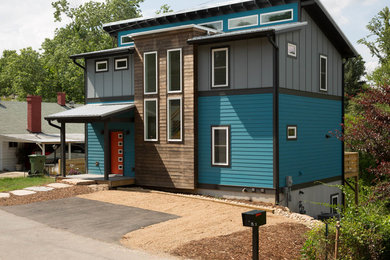 Cette photo montre une façade de maison bleue moderne de taille moyenne et à deux étages et plus avec un revêtement mixte, un toit en appentis et un toit en métal.