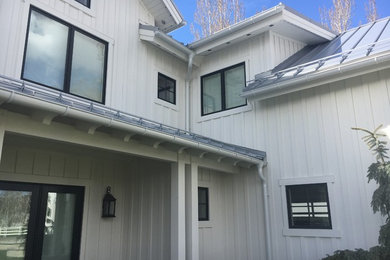 Ejemplo de fachada de casa blanca de estilo de casa de campo grande de dos plantas con revestimiento de madera, tejado a cuatro aguas y tejado de metal