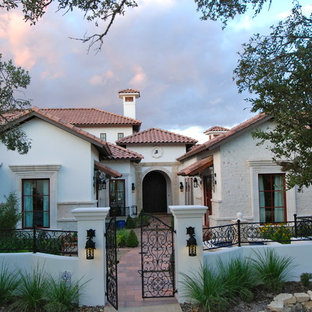 Foto della facciata di una casa unifamiliare ampia beige mediterranea a due piani con rivestimento in stucco, tetto a padiglione e copertura in tegole